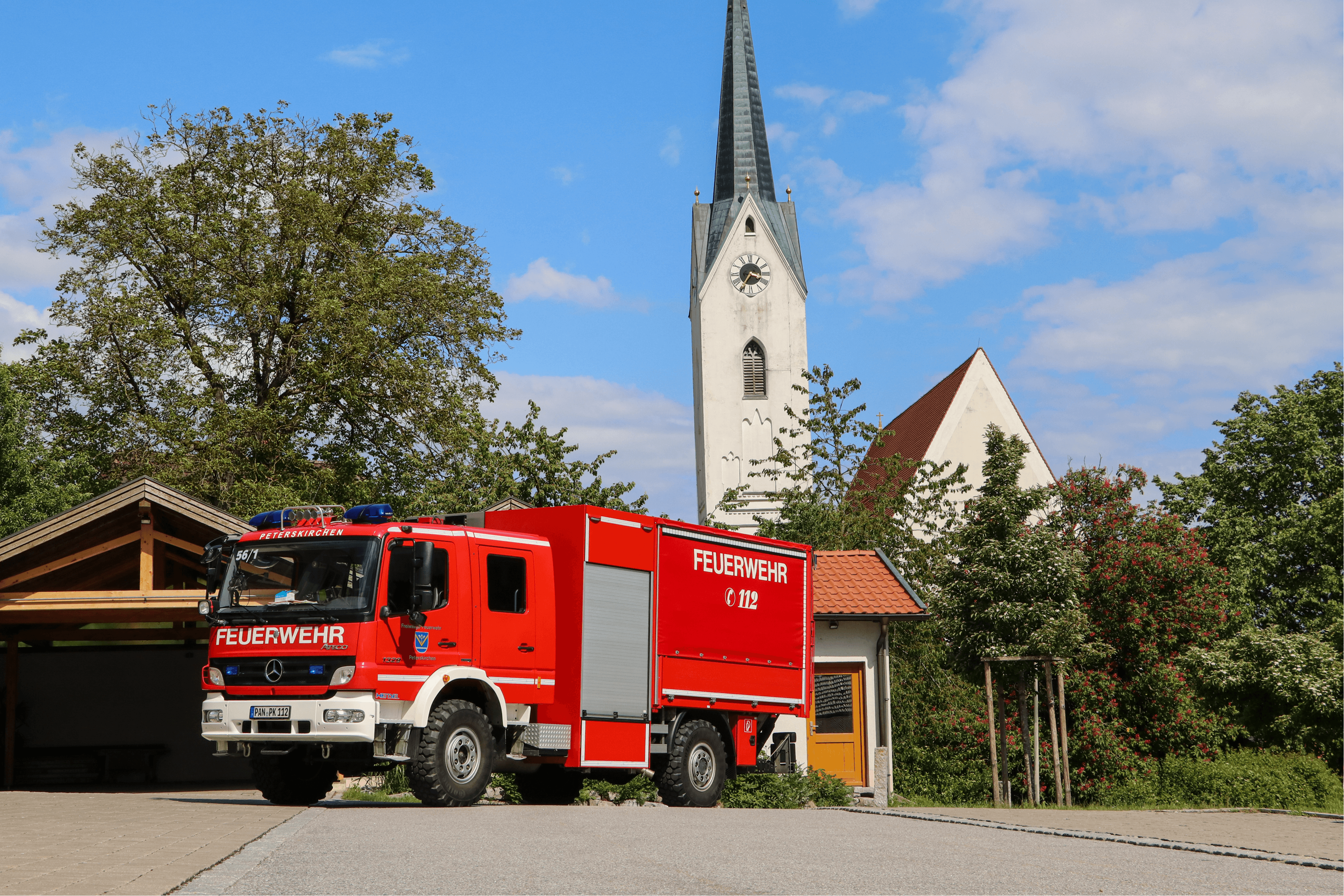 Löschfahrzeug (HLF) der Freiwilligen Feuerwehr Peterskirchen von vorne, im Hintergrund der Kirchturm von Peterskirchen