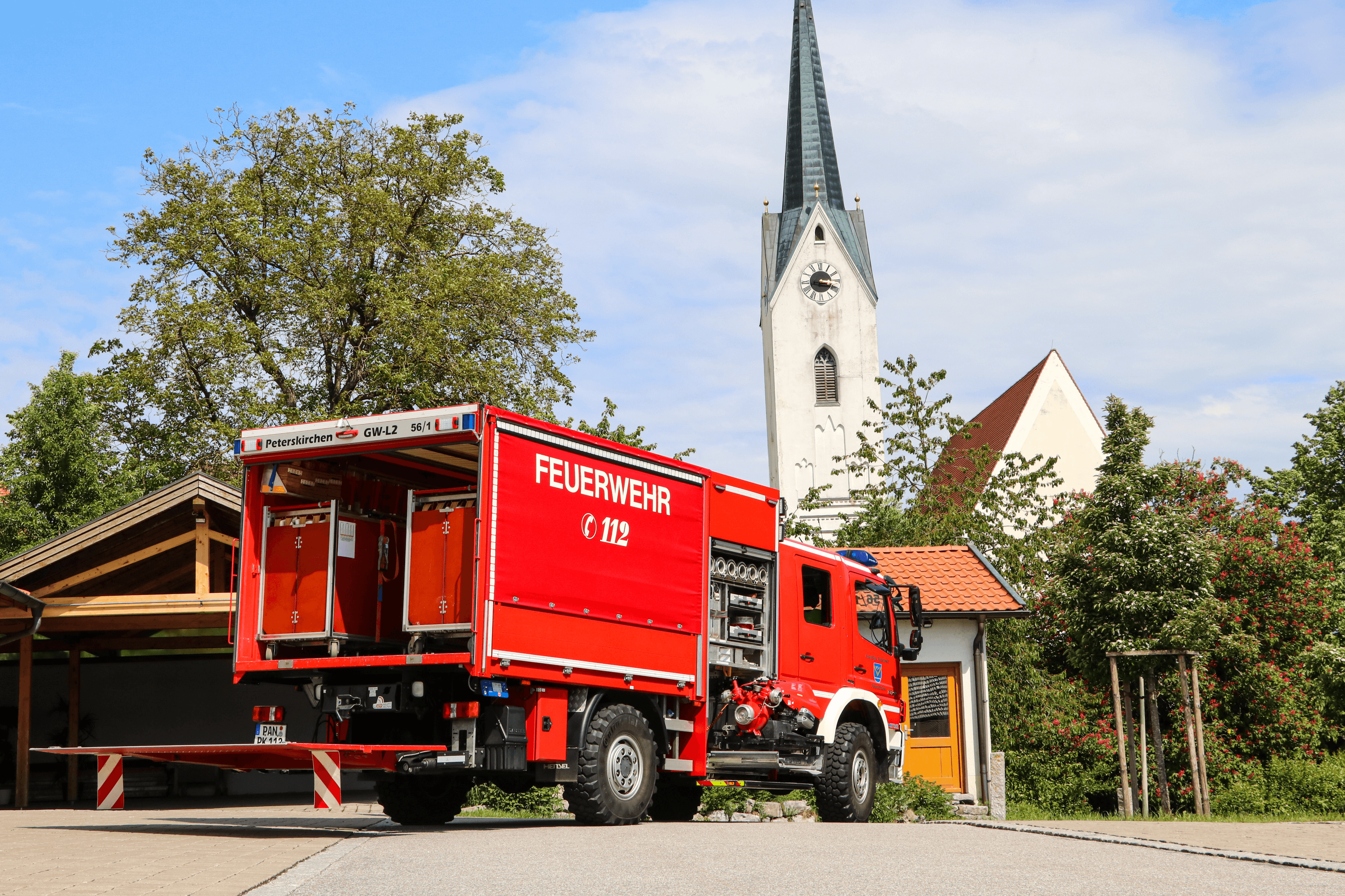Löschfahrzeug (HLF) der Freiwilligen Feuerwehr Peterskirchen von hinten, im Hintergrund der Kirchturm von Peterskirchen