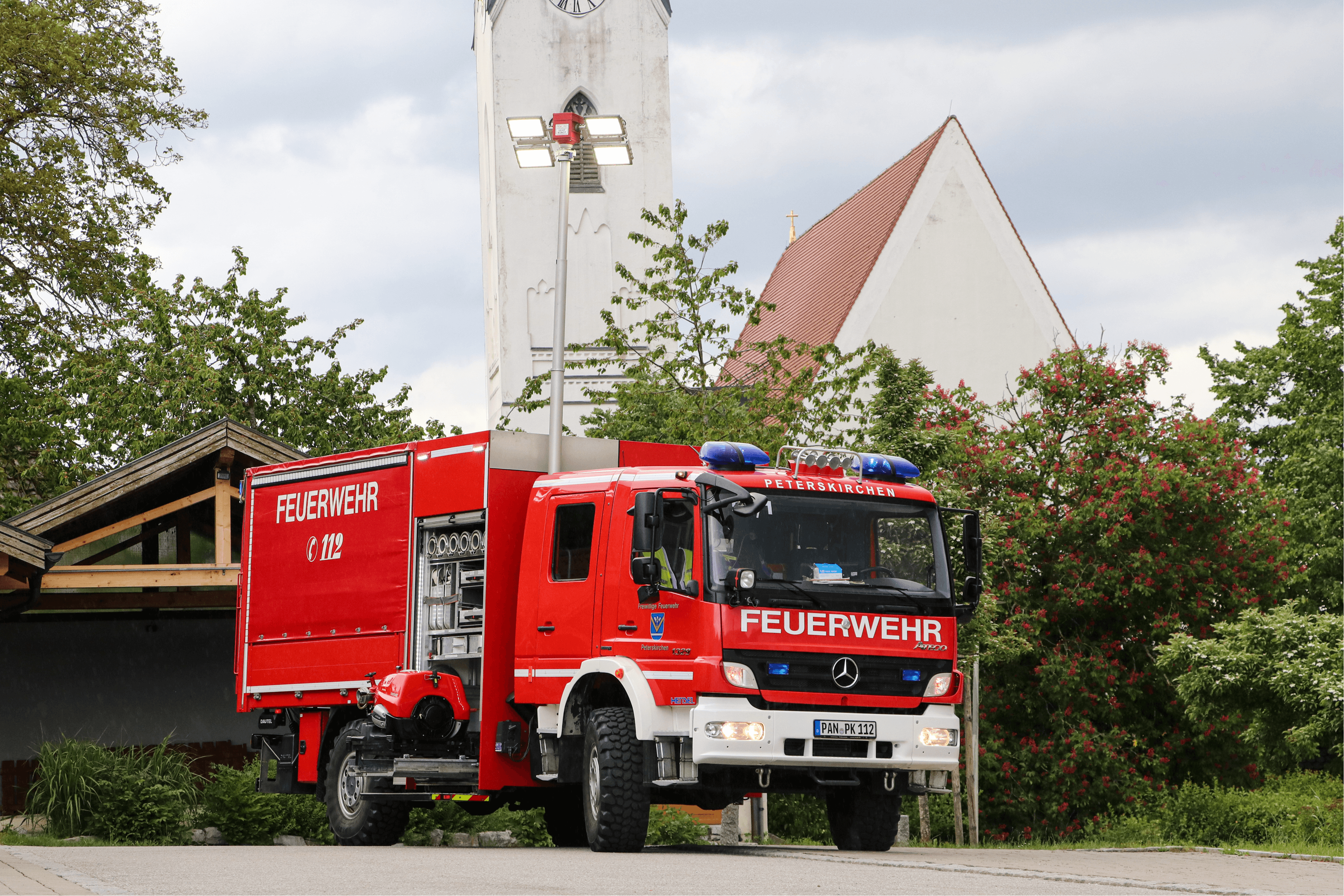 Löschfahrzeug (HLF) der Freiwilligen Feuerwehr Peterskirchen von hinten, im Hintergrund der Kirchturm von Peterskirchen